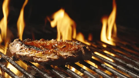 Steak on the grill with rising flames